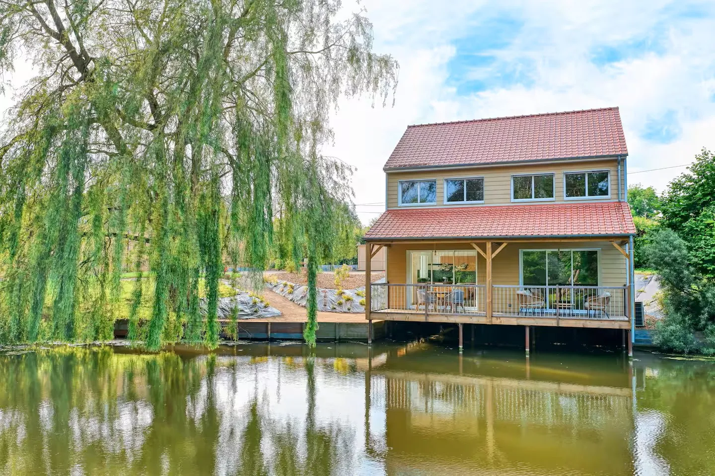 A house hanging on the water of its private pond