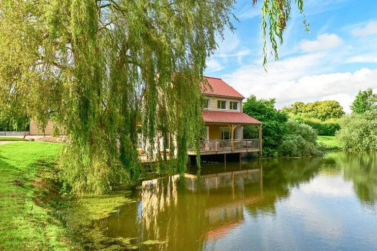 A house hanging on the water of its private pond